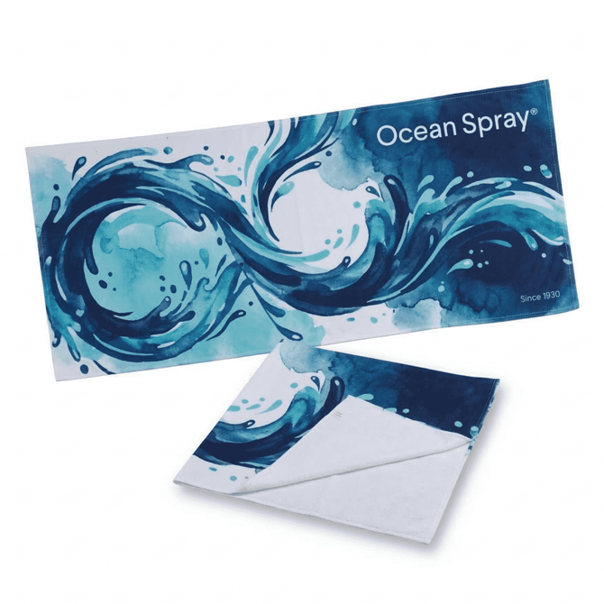 A beach towel featuring an abstract blue water design, measuring 180 x 90 cm, with a logo present.