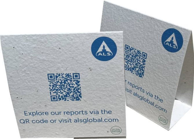 A white seed paper table tent card with a QR code and branding, featuring a textured surface with speckles.