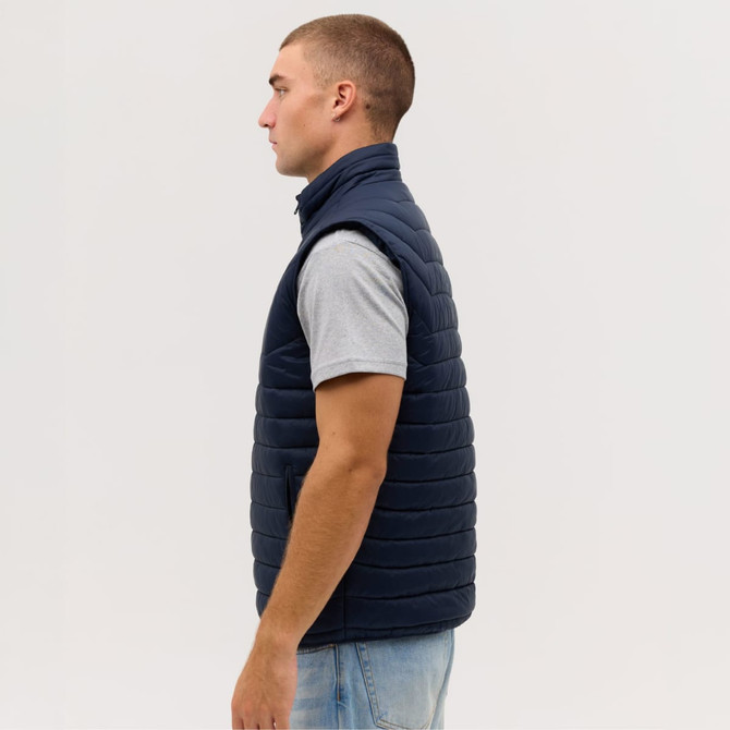A navy blue puffer vest displayed on a model from the side, featuring a high collar and a sleek design.