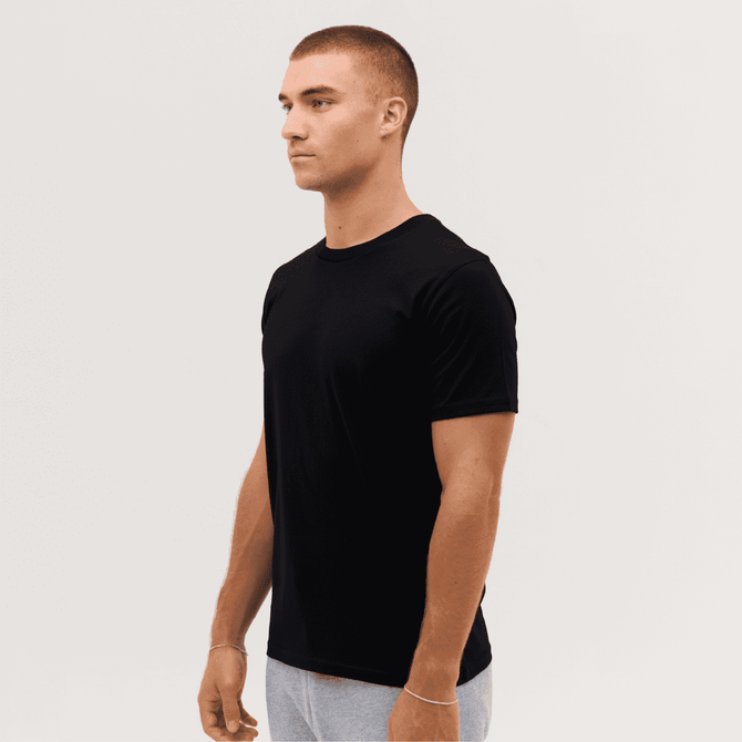 A black Classic Tee worn by a model standing sideways, with a simple, minimalistic design.