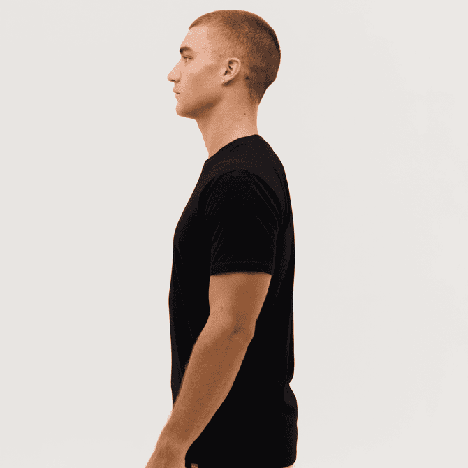 A black t-shirt is displayed on a model, shown from the side profile against a plain background.