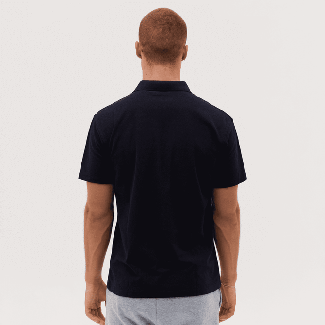 A man wearing a dark navy polo shirt, displayed from the back, with a simple design and a logo on the collar.