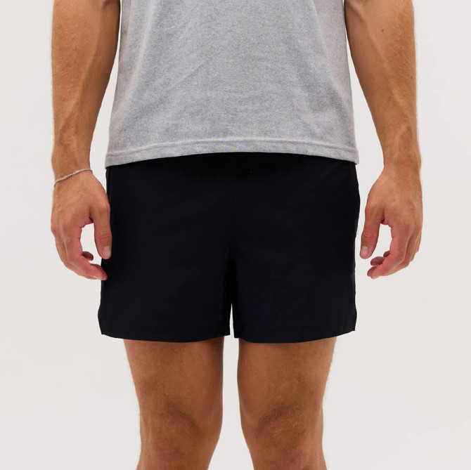 A pair of black running shorts, displayed on a person wearing a grey t-shirt, with a logo on the shorts.