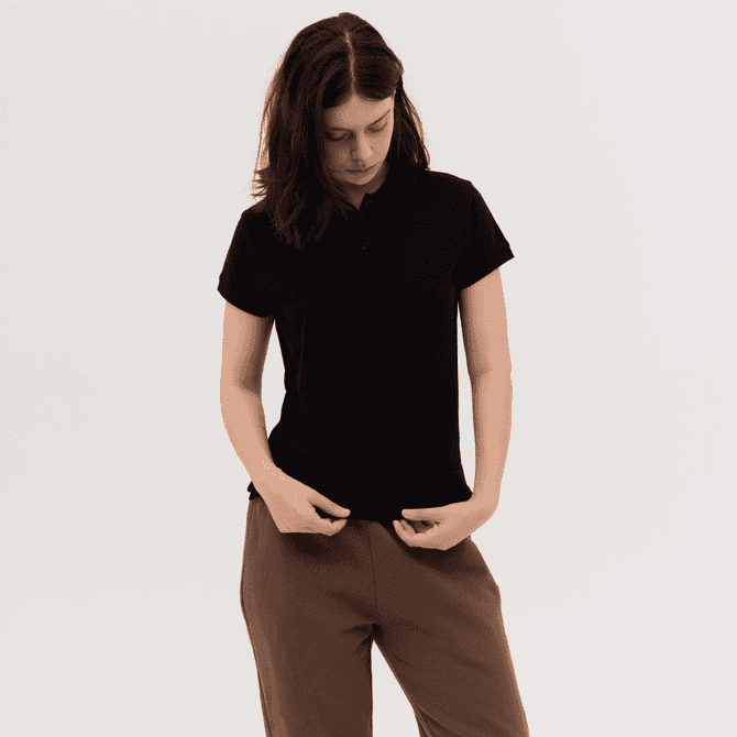 A women's polo shirt in black, featuring a collar and short sleeves, paired with loose-fitting trousers.