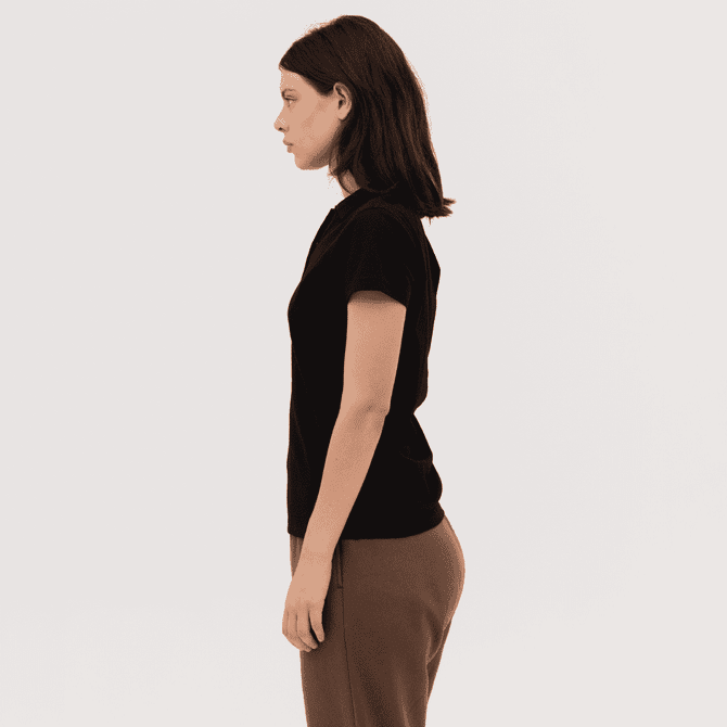 A black women's polo shirt displayed on a model, featuring a simple design and short sleeves.