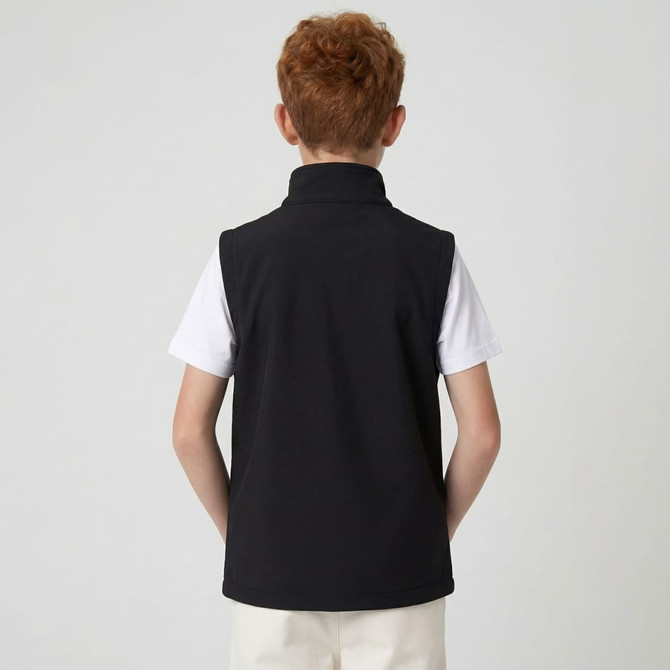 A black youth softshell vest with a high collar, worn over a white shirt, seen from the back.