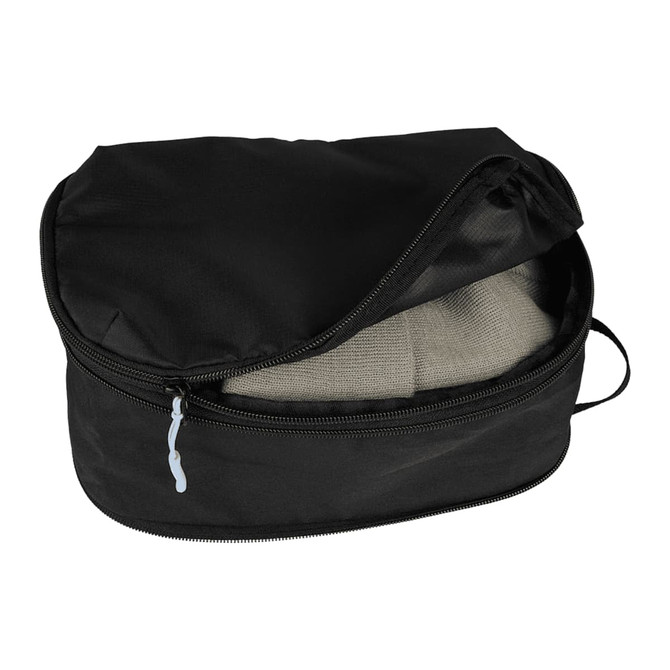 A black compression packing cube with a zippered opening, containing folded clothing inside.