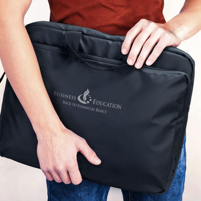 A person holding a sleek black laptop bag with a logo on the front and dual handles.