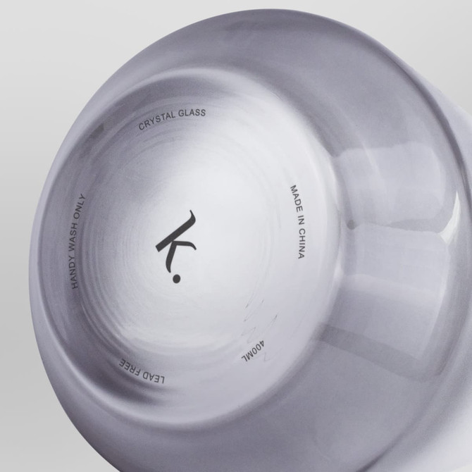 A crystal whiskey glass featuring a smooth finish, with a logo and text on the base. The glass is transparent.