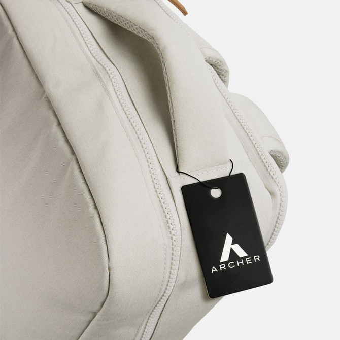 A light grey backpack with a handle and a tag attached, featuring a logo.