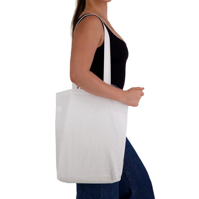 A white cotton long handle bag, held by a person wearing a black top, with the bag's branding visible.