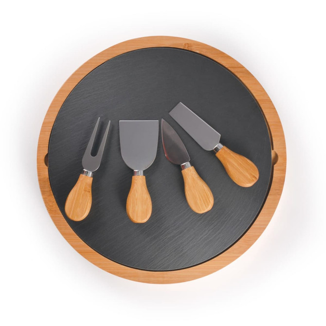 A round bamboo cheese board with a slate surface and four metal cheese knives with bamboo handles.