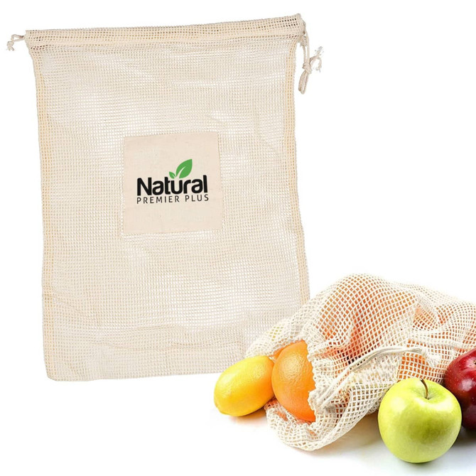 A beige mesh reusable produce bag next to various fresh fruits, including apples and oranges. The bag features a logo.