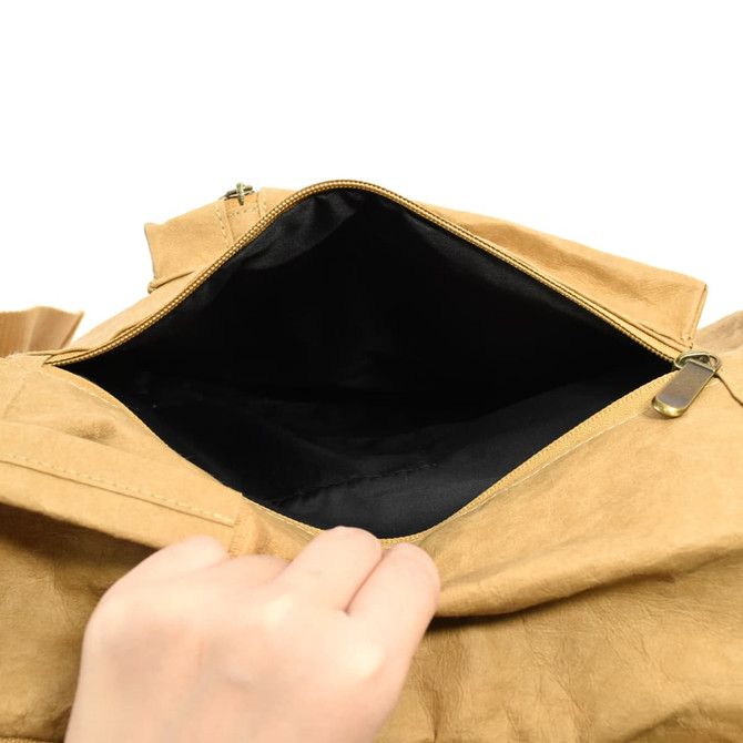 A hand reaching into a tan kraft paper laptop backpack, revealing a black interior and a zippered opening.