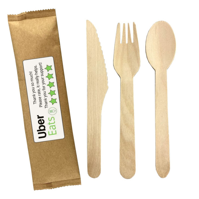 A wooden cutlery set featuring a knife, fork, and spoon, presented with a brown paper wrapper.