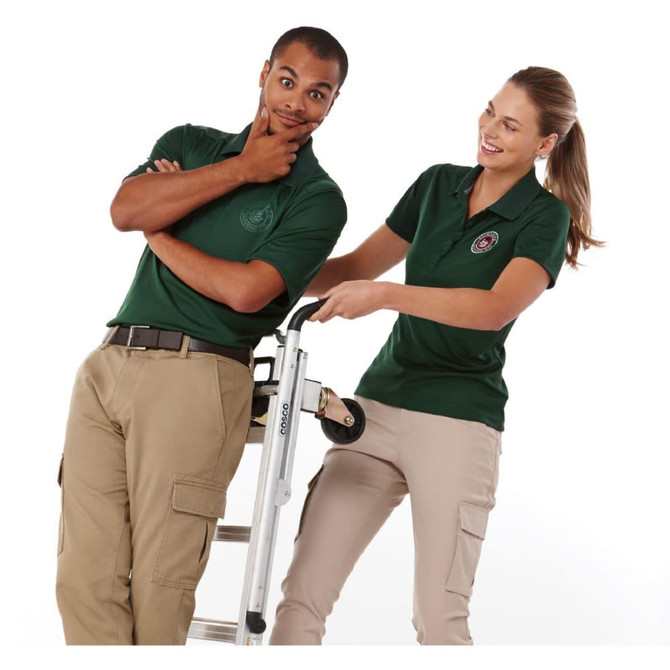Two models wear green short sleeve polo shirts, posing with a ladder, showcasing the shirts' fit and style.