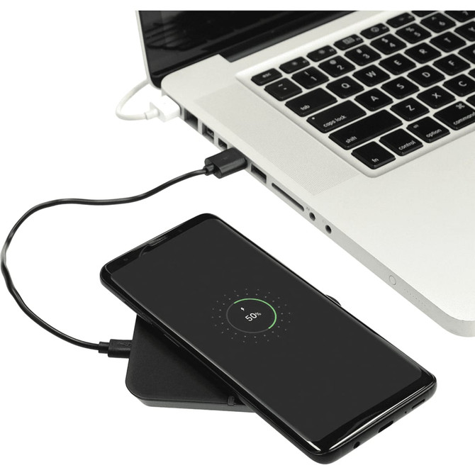 A wireless charging phone stand in black, with a smartphone on it, connected to a laptop by a charging cable.