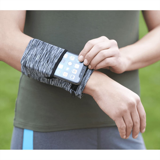 A heathered grey wristband with a pocket, holding a smartphone, worn on a person's arm against a green background.