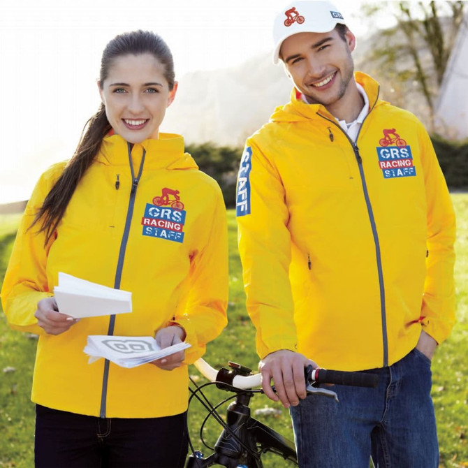 A lightweight jacket in bright yellow, featuring a logo, worn by two models outdoors, one with a bicycle.