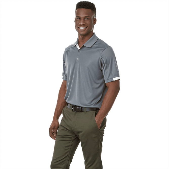 A grey short sleeve polo shirt with a logo, paired with green trousers, worn by a smiling male model.