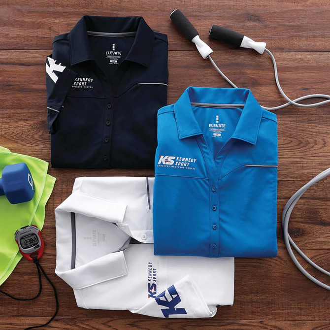 Multiple short sleeve polo shirts in navy, blue, and white, featuring a logo, arranged on a wooden surface with fitness equipment.