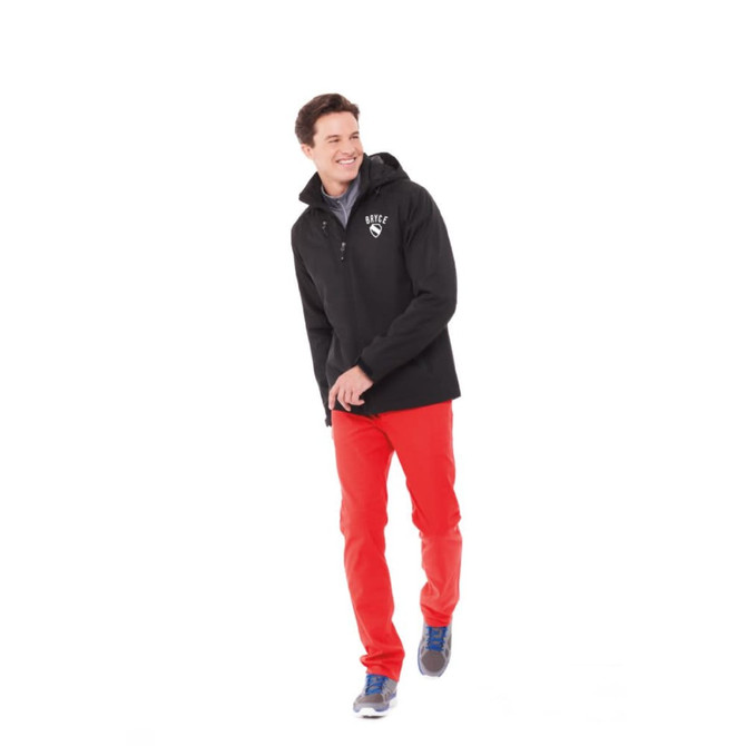 A man wearing a black insulated softshell jacket and red pants, walking in a casual style. The jacket has a logo.