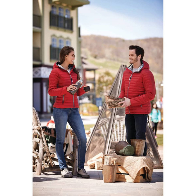 A red puffer jacket with a hood, worn by a man and a woman outdoors, with a logo visible on the jacket.