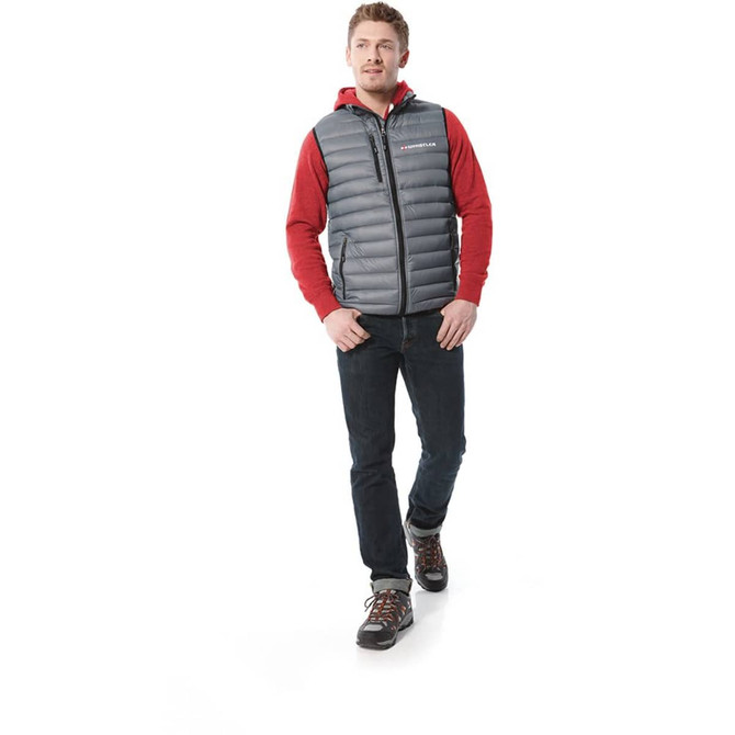 A man walks in a grey down vest over a red hoodie, paired with dark jeans and hiking boots. The vest has a logo.