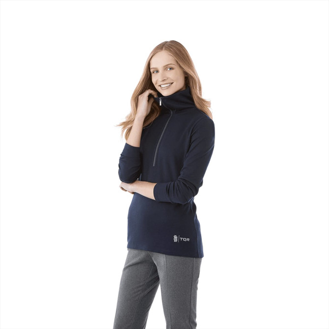 A woman wearing a navy knitted half zip jumper with a high collar. The jumper features a branded logo.