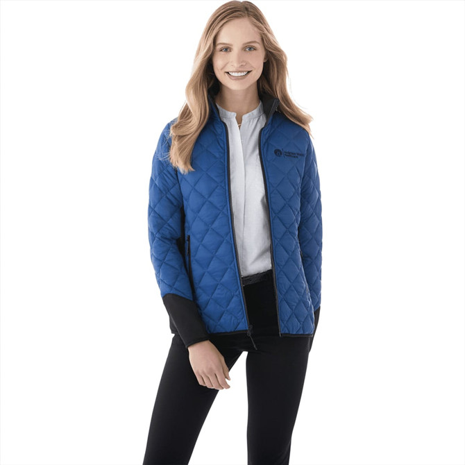 A woman wearing a blue quilted insulated jacket with a black collar and branding.