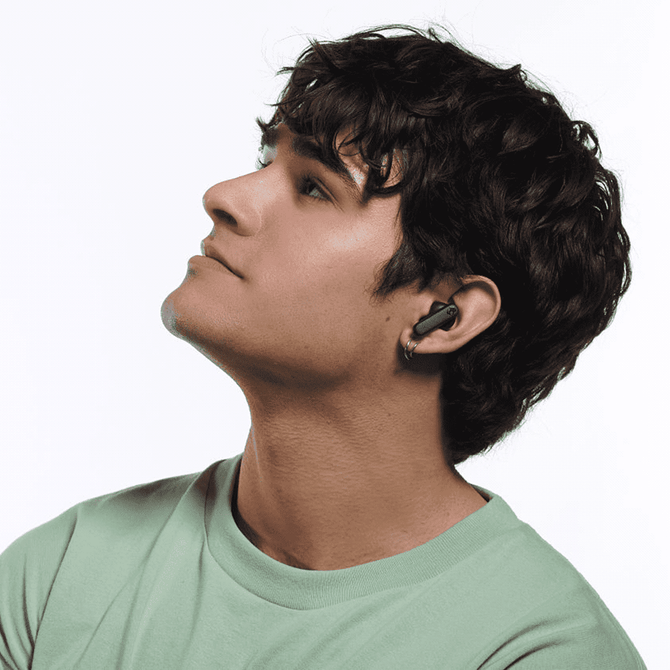 A person wearing black Skullcandy Smokin' Buds earbuds, looking upwards against a plain background.