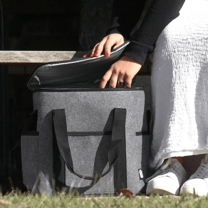 A drink bottle cooler bag in grey felt with black straps, being opened to reveal its interior.