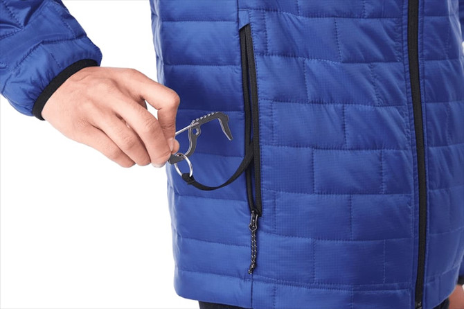 A blue insulated puffer jacket with a hand placing a tool into a zipped pocket. The jacket features a logo.