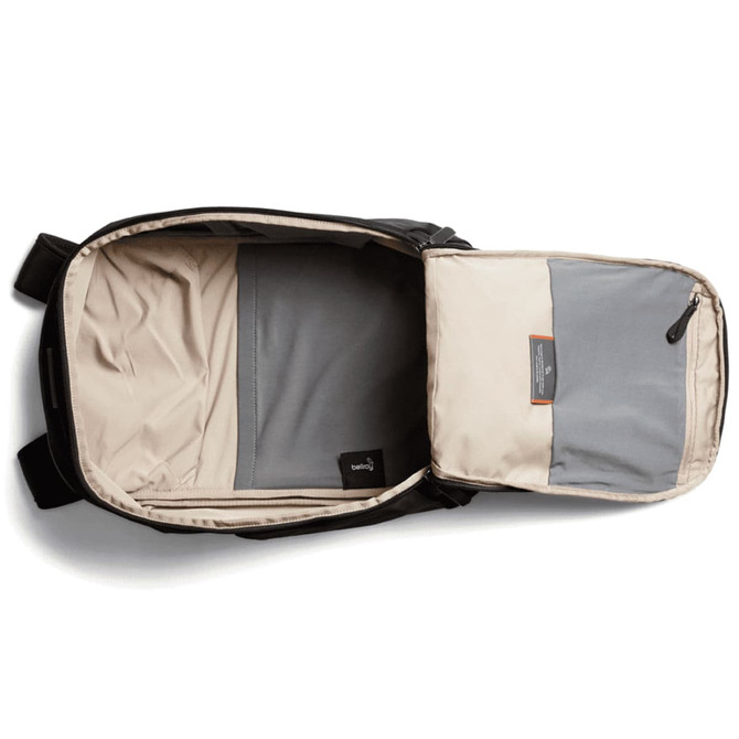 A black backpack with a beige interior and a grey compartment, featuring a logo on the outside.
