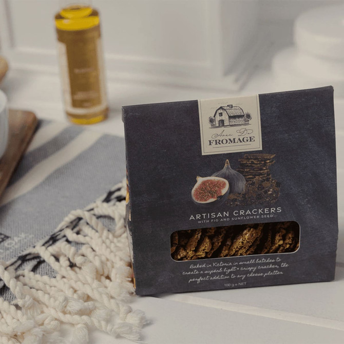 A pack of artisan crackers in a dark box with figs and sunflower seeds, with a logo on the front.