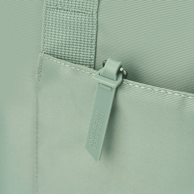 A mint green tote bag featuring a zippered pocket and textured fabric, with a logo on the zipper tag.