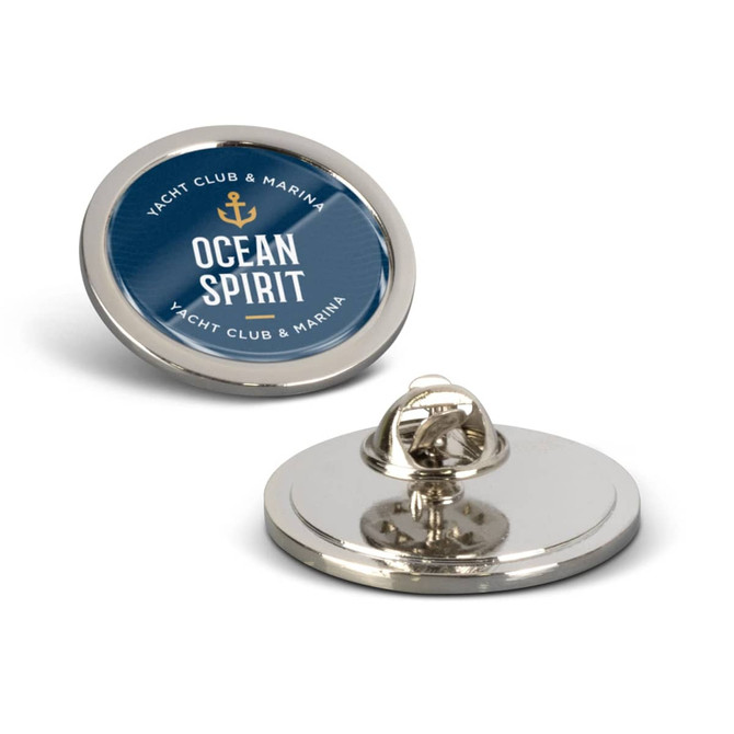 A round large lapel pin featuring a blue and gold design with a logo. The pin has a shiny silver backing.