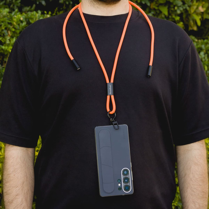 An orange phone lanyard is worn around the neck, holding a smartphone. The lanyard has a sleek design with attachments.