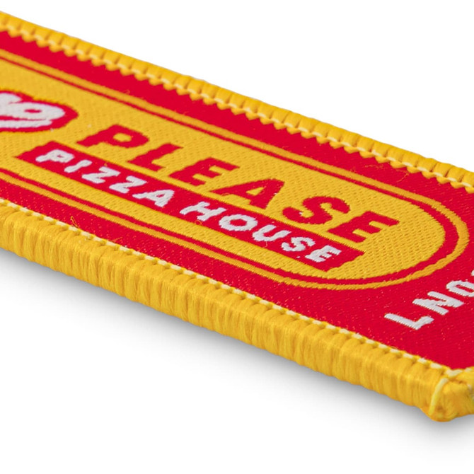 A woven keytag in red and yellow with a branded logo and text design.
