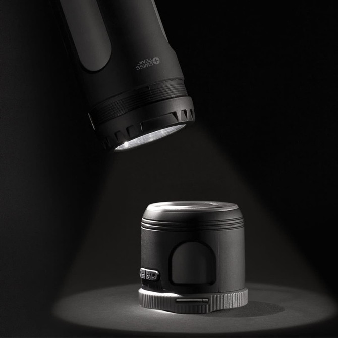 A black Swiss Peak 4-in-1 speaker illuminated by a flashlight, showcasing its sleek design and functionality.