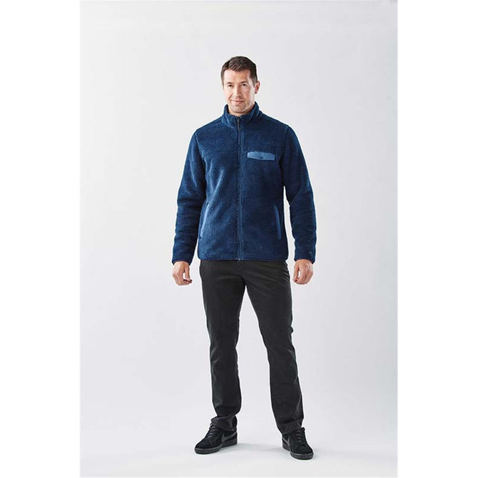 A man wearing a navy blue men's Bergen Sherpa fleece jacket, paired with black pants and dark shoes.