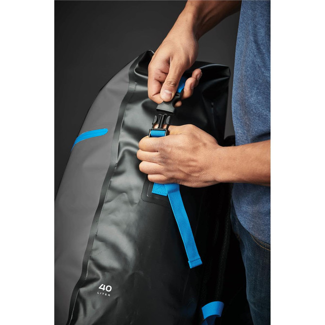 A person adjusts a blue strap on a black and grey Kemano Backpack, featuring a logo and a 40-litre capacity.