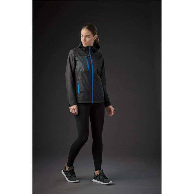 A woman wearing a black rain jacket with blue accents, paired with black leggings and sneakers.