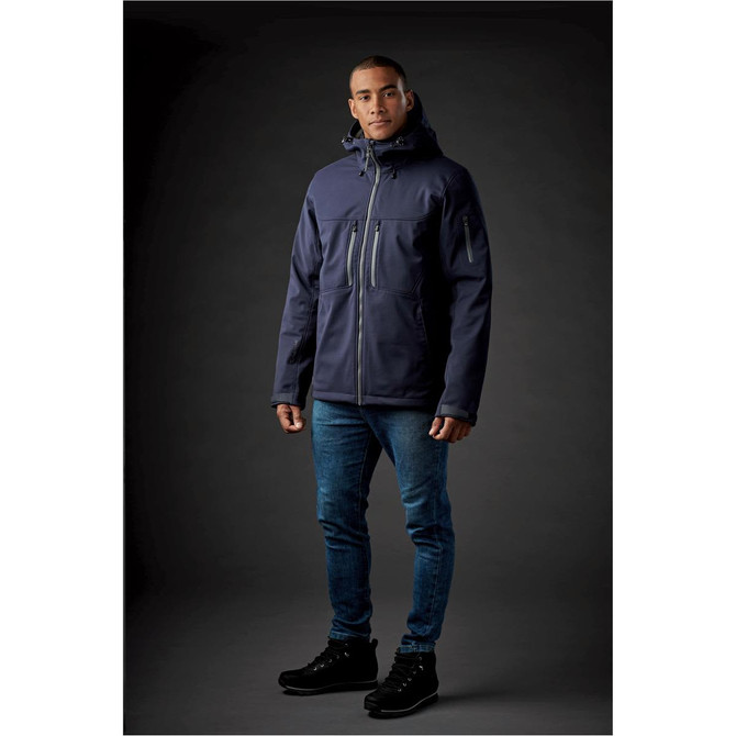 A navy jacket with a hood and zippers, worn by a model against a dark background. The jacket features a logo.
