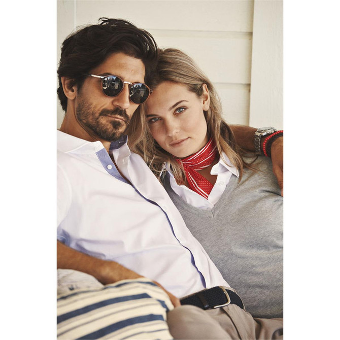 A man in sunglasses and a woman in a shirt and scarf sit together, featuring a casual, stylish vibe.