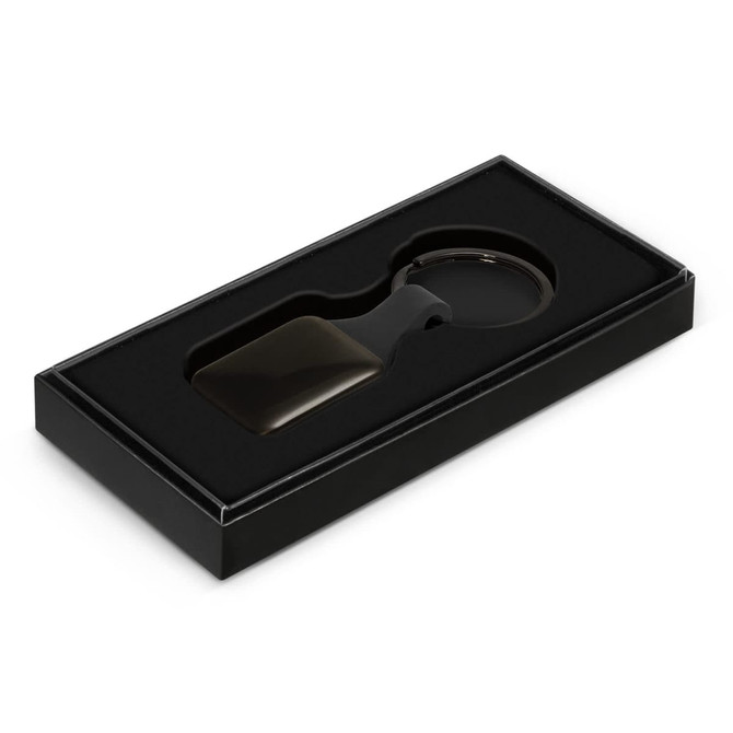 A key ring in a square shape is presented in a black box with a cushioned interior.
