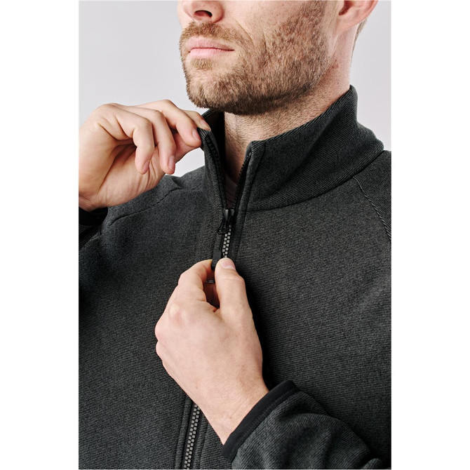 A men's full zip jacket in dark grey, being zipped up by a man. Features a collar and a logo.