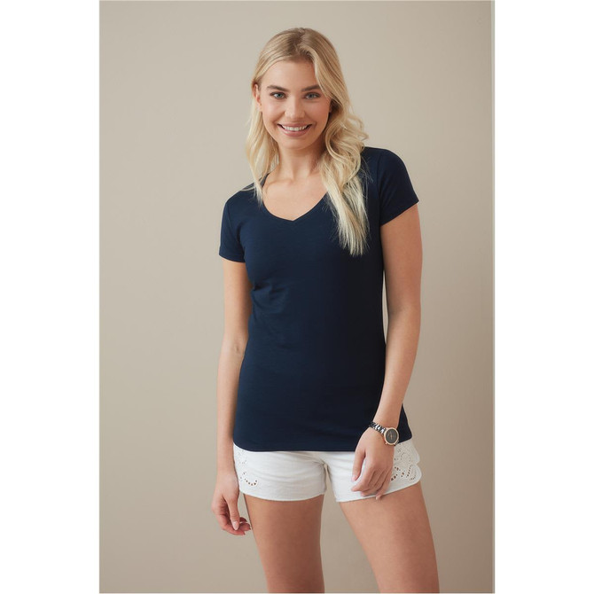 A woman wearing a navy blue V-neck T-shirt paired with white shorts, smiling at the camera. The shirt features a logo.