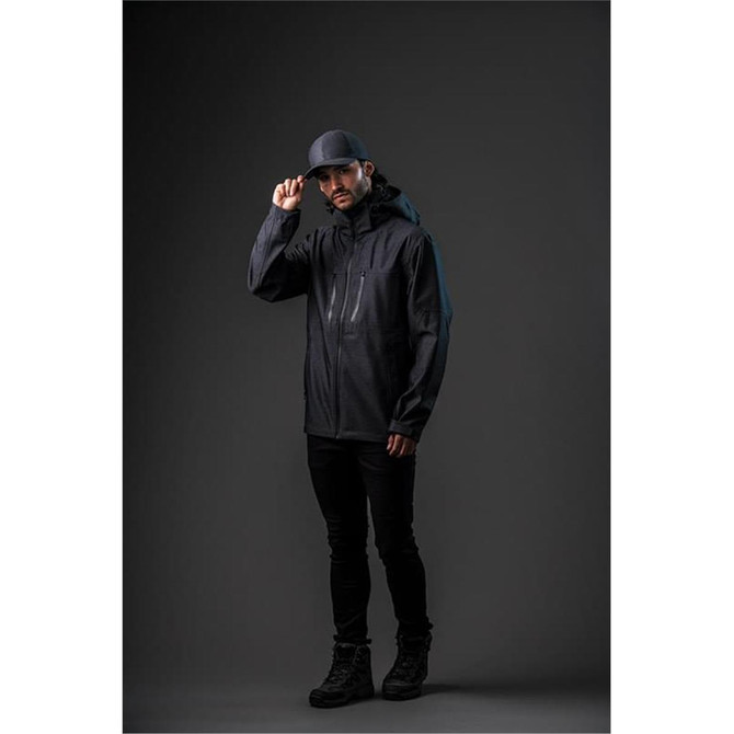 A man wearing a black Men's Patrol Softshell jacket and cap, standing against a dark background. The jacket has a logo.