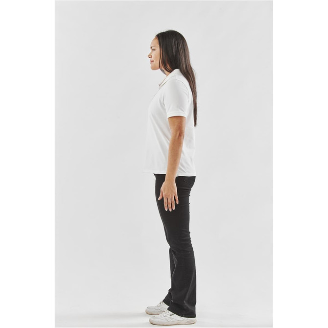 A white women's polo shirt is displayed, styled with black pants and set against a plain white background.